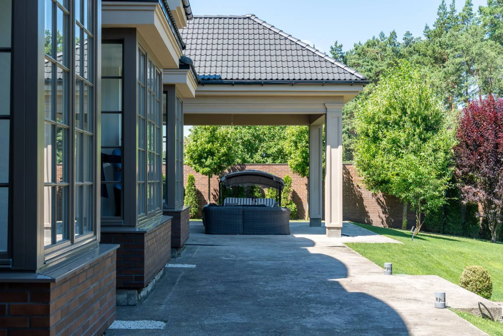 Covered concrete patio beside a green lawn and garden
