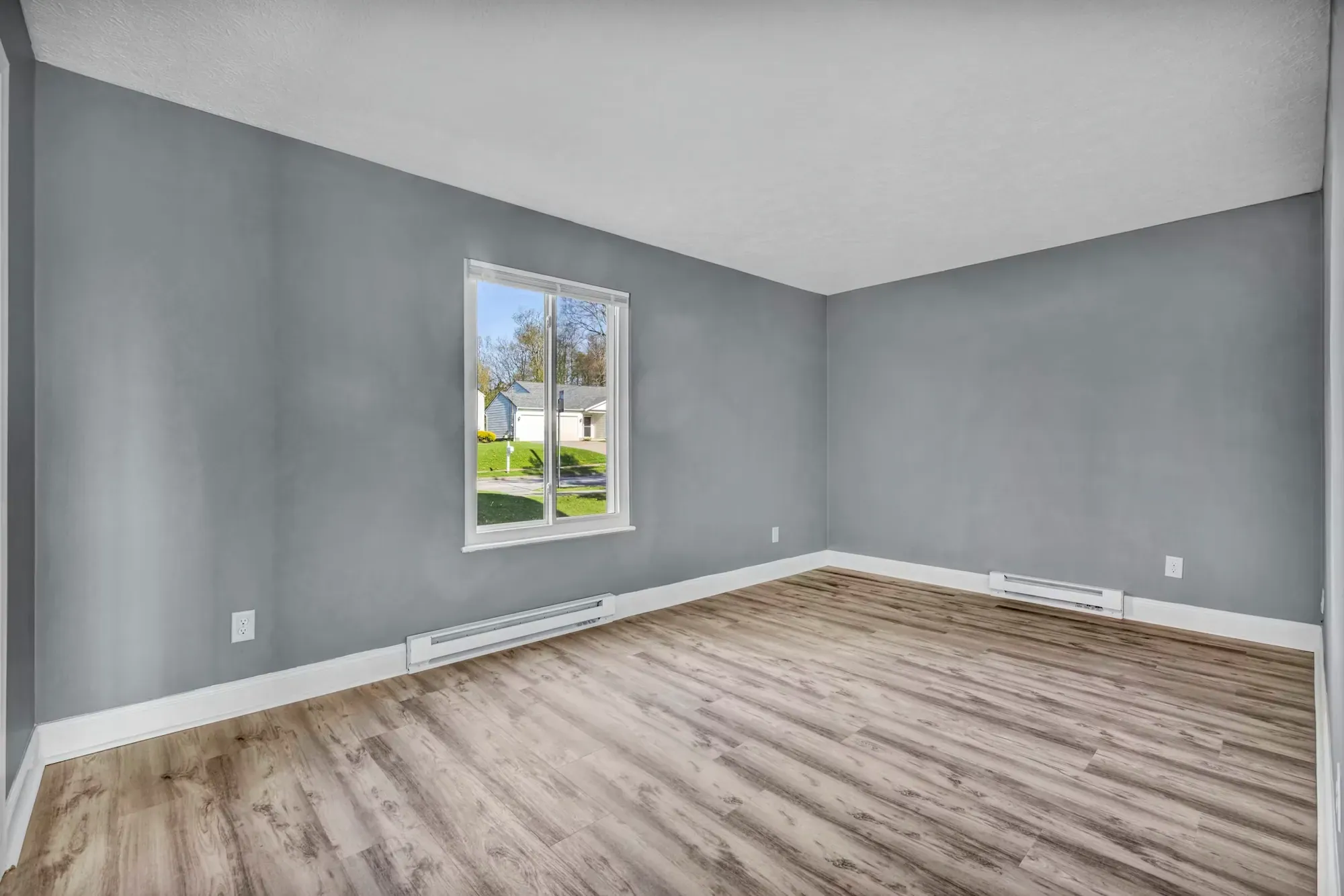 Empty room with grey walls and new wood-look laminate planks