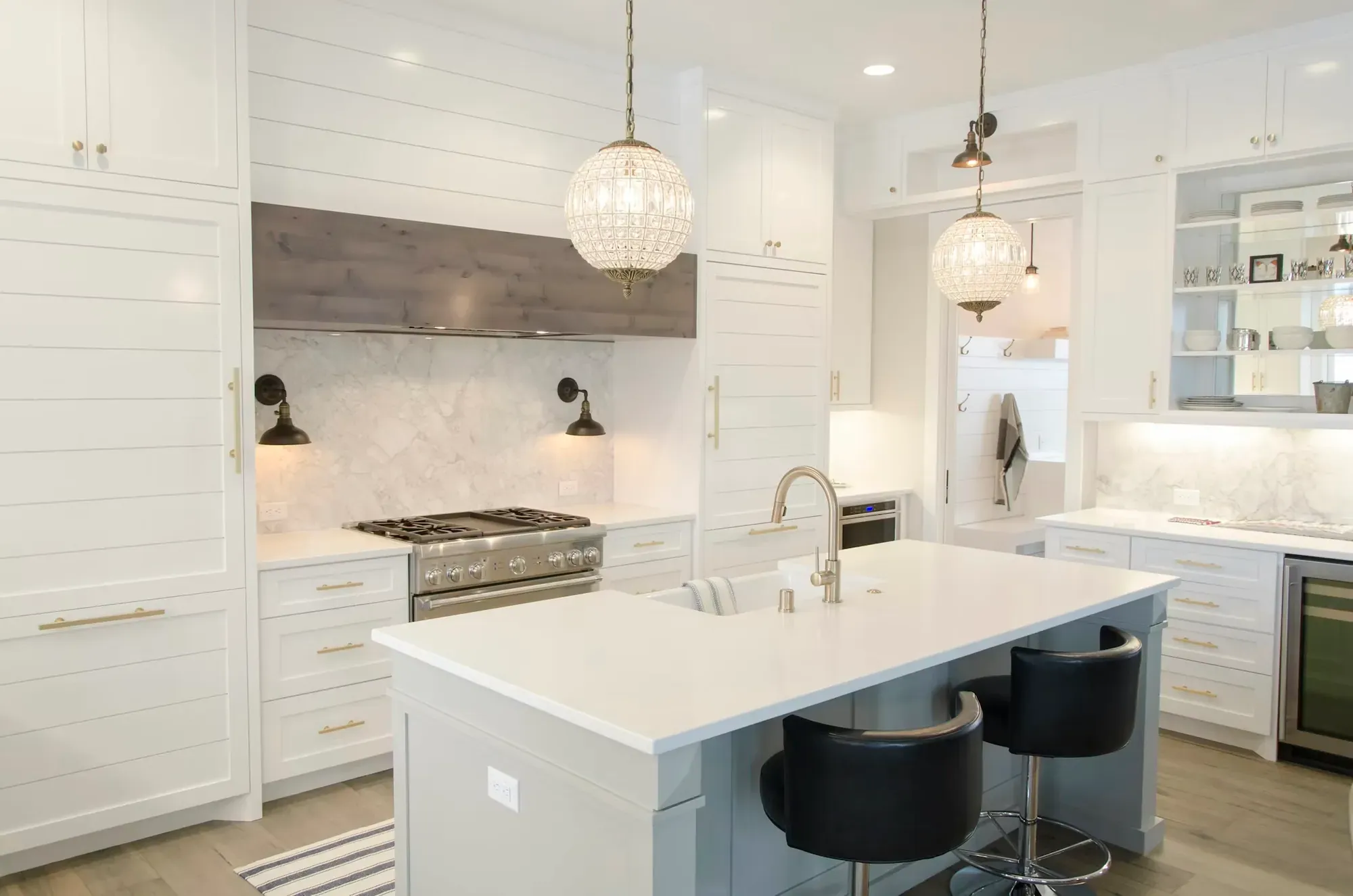 Remodeled white kitchen with a marble backsplash, island and pendant lights